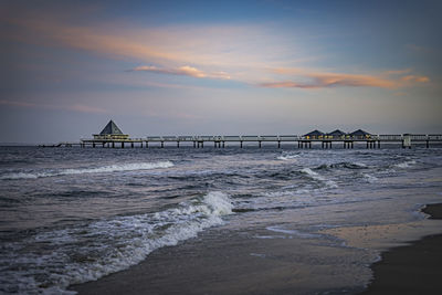 Pier over sea against sky during sunset