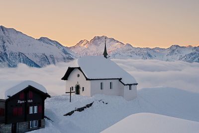 Snow covered houses and mountains against sky