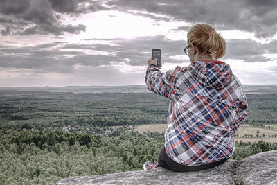 Long hair cute girl take picture by smart phone. morning hilly landscapewith few clouds of mist.