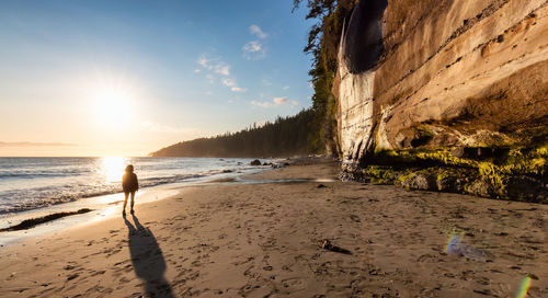 Man standing on beach against sky during sunset