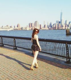 Rear view of young woman against sea and cityscape