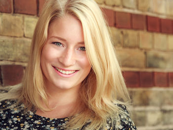 Portrait of smiling woman against wall