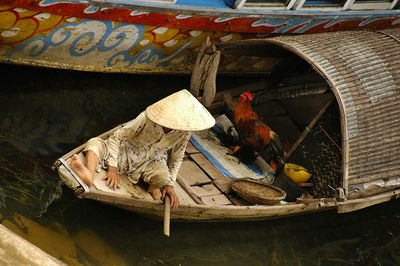 High angle view person by rooster on boat moored in river