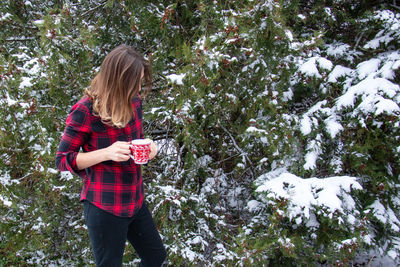 Full length of a woman holding snow covered tree