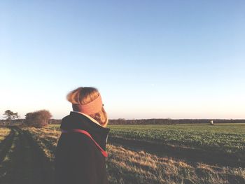 Woman standing on field against clear sky