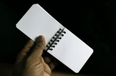 High angle view of person holding paper against black background