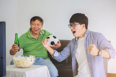 Cheerful father and son enjoying soccer match at home