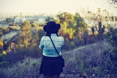 Rear view of woman standing amidst grass