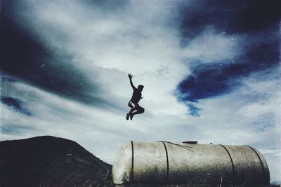 Low angle view of kite flying against cloudy sky