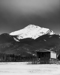 A snow capped peak, byers peak, towers above a hay barn of a ranch in the valley below