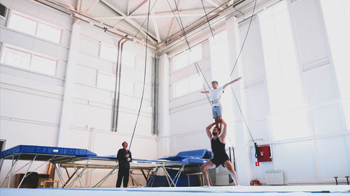 Instructor with teenage boy practicing gymnastics in club