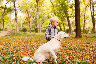 Boy with dog in forest during autumn