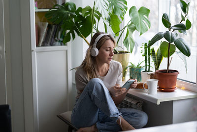 Woman using mobile phone while sitting at home