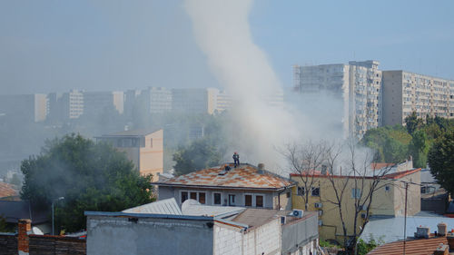 Smoke emitting from buildings in city against sky