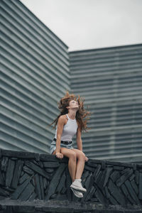 Woman looking away while standing against wall