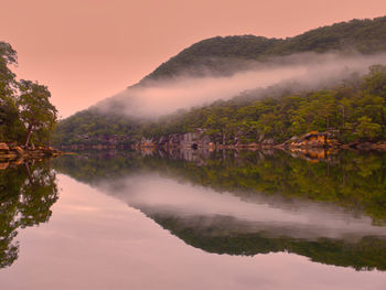 Scenic view of lake by mountains against sky during sunset