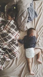 Directly above view of siblings sleeping on bed at home