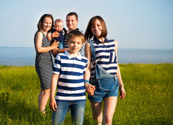 Full length of friends standing on sea shore against sky