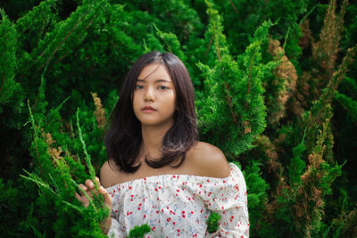 Portrait of beautiful young woman against plants