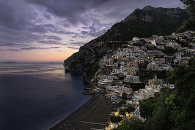 Townscape by sea against sky during sunset