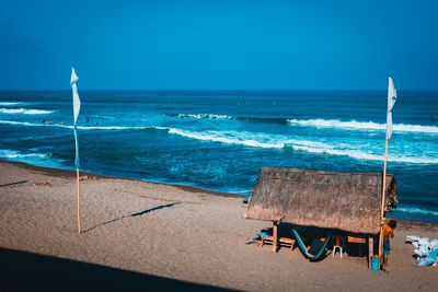 Deck chairs on beach against clear blue sky