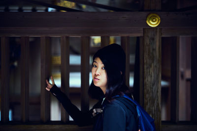 Portrait of beautiful woman standing against railing