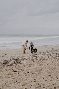 Young attractive couple having fun at he beach with a dog