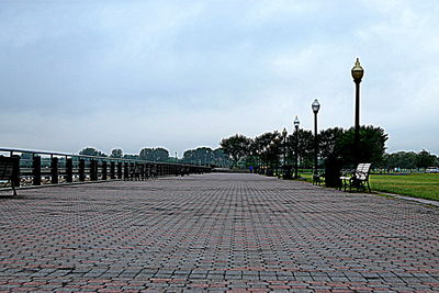 Sidewalk by beach in city against sky