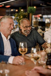 Cheerful male friends with wineglasses enjoying while sitting in restaurant