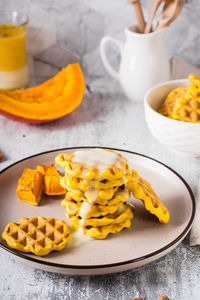 A stack of pumpkin waffles with sweet sauce on a plate on the table. homemade baking. vertical view