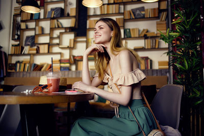 Young woman looking up while sitting on table at restaurant