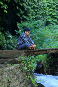 Rear view of man sitting on rock