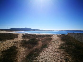 Scenic view of beach against clear blue sky