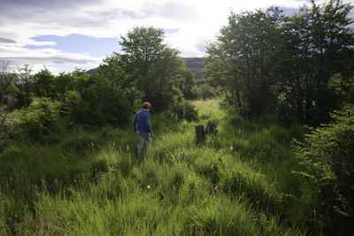 Rear view of man walking on land against sky