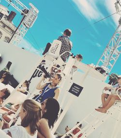 Low angle view of people photographing against sky