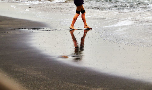 Low section of woman standing on wet beach