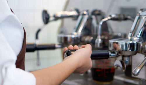 Coffee shop staff dressed in brown apron making fresh espresso coffee.