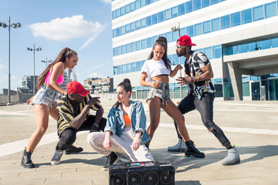 Friends dancing against building in city