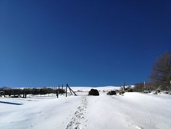 Snow covered road against clear blue sky