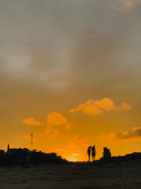 Silhouette people on beach against sky during sunset