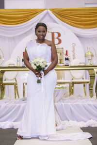 Portrait of young woman standing at top table