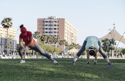 Men with arms outstretched against sky in city