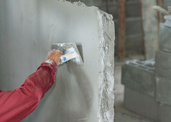 Close up hand worker plastering cement on wall for building house.