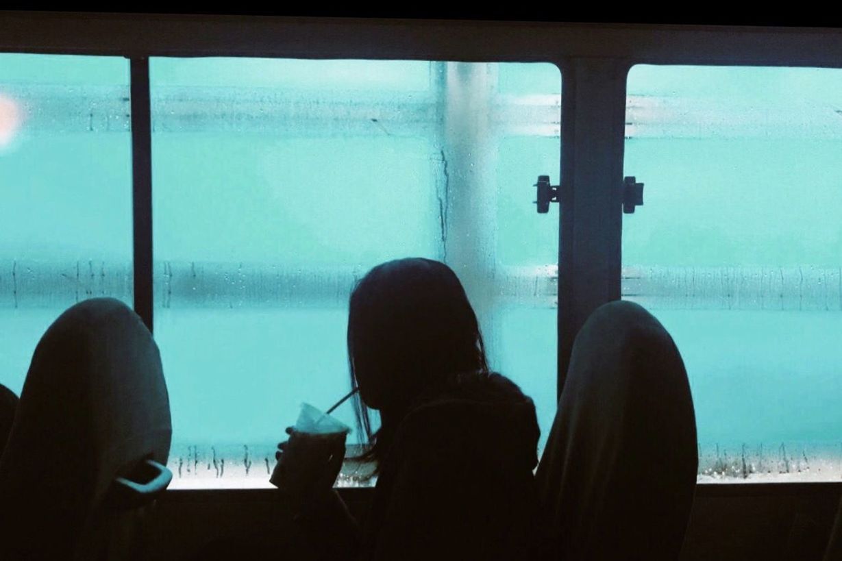 REAR VIEW OF MAN LOOKING AT SWIMMING POOL AGAINST WINDOW