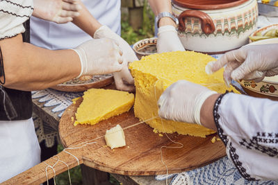 Woman's hands cut polenta on the table with romanian ornaments