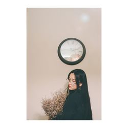 Young woman standing against white wall