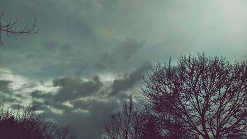 Low angle view of bare tree against cloudy sky