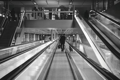 Rear view of woman walking on escalator