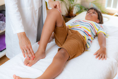 Pediatric doctor doing medical exam with boy on bed.