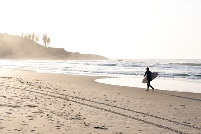 Unrecognizable man running with surf board at the beach